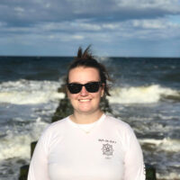 Photo of Courtnie Park standing on an old pier on a sunny day in the Atlantic Ocean in Delaware, USA