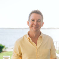 Patrick Flynn Headshot in front of a pier with water in the background